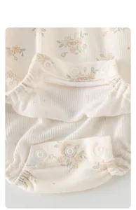 Détail d'un body bébé à fleurs avec boutons-pression et tissu côtelé ultra-doux