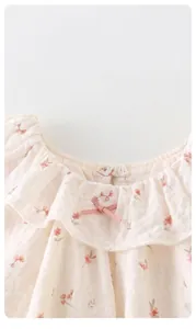 Detail der Blumen-Babybluse mit Rüschenkragen, rosa Schleife und ohne Fluoreszenzmittel