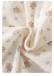 Dettaglio del tessuto in maglia floreale con rose rosa e pois per pagliaccetti da neonato