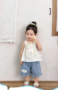 Detail of floral ruffle top with bear embroidery and matching denim shorts for baby girls