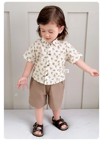 Dettaglio camicia estiva beige per bambini con motivi anatra e pantaloncini kaki