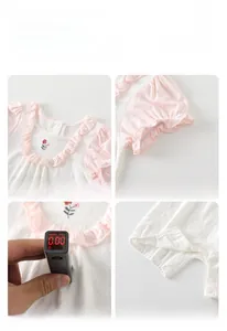 Détail d'un barboteuse bébé rose avec volants, broderie florale et test sans fluorescence