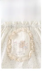 Detail of floral infant tank top with lace-edged bear patch and soft cotton fabric