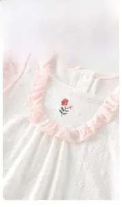 Détail du col de la barboteuse pour bébé avec volants roses et fleur brodée