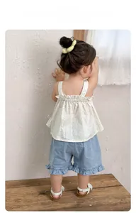 Detail of floral ruffle camisole and denim shorts on a toddler girl for summer outfit