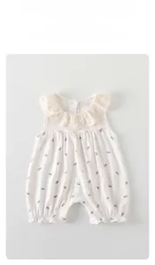 Detail eines Baby-Bodys mit Blumenmuster, Spitzenkragen und Druckknöpfen am Boden