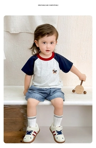 Detail of embroidered rocking horse on raglan sleeve t-shirt and light blue denim shorts