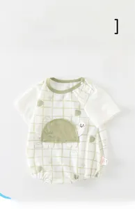 Detail of breathable baby romper with green plaid pattern and turtle embroidery