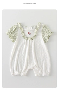 Détail de barboteuse bébé avec col à volants, broderie florale et texture jacquard