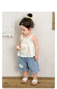 Close-up of floral camisole top with ruffle trim and denim shorts for toddler girls
