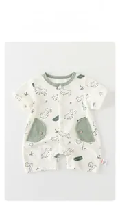 Close-up of baby summer romper featuring cartoon dinosaur prints and wooden buttons