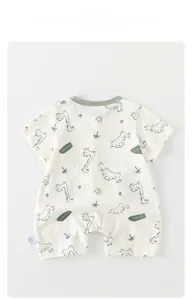 Detailed view of beige baby romper with green dinosaur print and soft cotton fabric texture