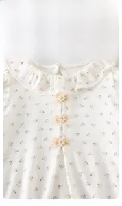 Détail d'un body floral pour bébé avec col à volants et trois boutons fleurs en 3D