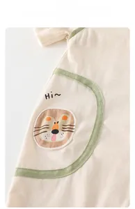 Detail of baby cotton bodysuit featuring a lion patch pocket and soft green trim