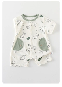 Detail of baby summer romper with green dinosaur print and wooden buttons on pockets