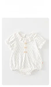 Détail d'un barboteuse bébé à fleurs avec col à volants et petits nœuds roses doux