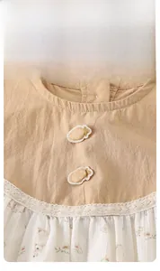 Detail of infant bodysuit featuring cotton fabric with strawberry patches and lace collar