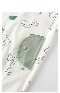 Macro detail of breathable cotton baby romper featuring green dinosaur print and side pocket