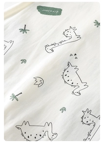 Close-up of baby romper fabric with cute dinosaur and palm tree prints on white cotton