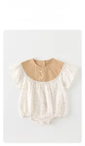 Detail of baby romper featuring lace collar and floral print on soft cotton fabric