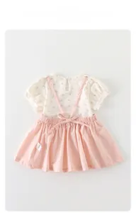 Detail of floral infant bodysuit and pink suspender dress set with bow and wash label
