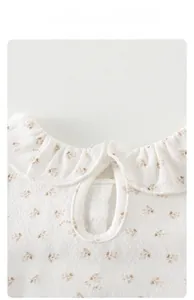 Détail du body fleuri pour bébé avec col à volants et tissu en coton tricoté respirant