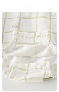 Close-up of snap closures on breathable green plaid baby bodysuit with mushroom pattern