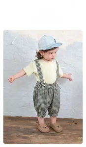 Details zum Baby-Outfit mit gelbem T-Shirt und Vintage-Latzhose mit Karomuster