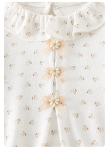 Détail du col volanté sur body bébé fleuri avec nœuds en dentelle et fleurs en 3D