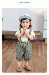 Detailansicht der Baby Sommerkleidung mit gelbem T-Shirt und grün karierter Latzhose