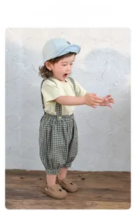 Detail eines Baby-Sommeroutfits mit atmungsaktivem Baumwoll-T-Shirt und karierter Latzhose