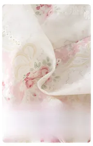 Détail du tissu pour bébé blanc crème avec imprimé floral rose et broderie anglaise