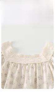 Détail d'un haut floral pour bébé fille avec col carré et dentelle brodée ajourée
