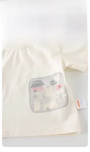 Détail d'un t-shirt bébé en coton avec imprimé de dessin animé ours et maison