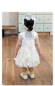 Detail view of baby floral suspender dress featuring back zipper and lace headband