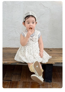 Flat lay of floral baby dress set with matching grey vest and lace accessories
