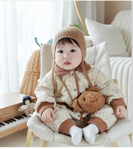 Close-up of quilted baby romper with cartoon bear print and knit hat accessories