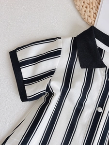 Detail of baby polo romper featuring black and white vertical stripes and ribbed collar
