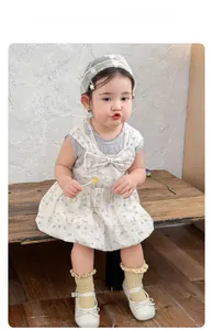 Detail of floral baby girl dress set with grey ruffle top and large beige bow accent