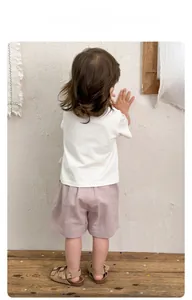 Vue arrière d'un enfant portant un t-shirt blanc et un short violet avec sandales