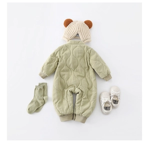 Flat lay of warm padded baby romper with double zippers, knit hat, socks, and infant shoes
