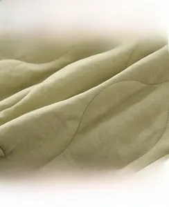 Detail of light green quilted baby winter fabric showing wave pattern and high-density weave