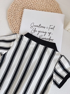 Detailed view of striped cotton baby polo romper with textured knit fabric on flat lay