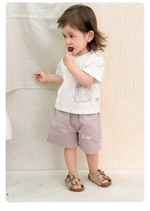 Détail d'une tenue d'été pour enfant avec t-shirt ours blanc et short violet