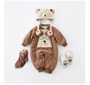Flat lay of warm quilted baby romper with bear hat, socks, and shoes for winter