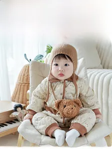 Detail of baby quilted romper with bear patterns, matching knit hat and plush bag