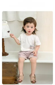 Détail de l'ensemble bébé garçon avec t-shirt blanc et short rose en coton doux