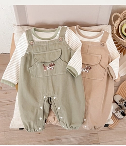 Detailed view of baby overalls with cute dog embroidery and striped cotton undershirts