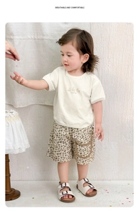 Dettaglio completo del set estivo neonato con t-shirt beige e pantaloncini leopardati