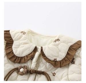 Détail du haut matelassé pour bébé avec col claudine brodé de fleurs et bord volanté